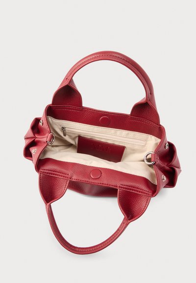 Κόκκινη δερμάτινη τσάντα με δύο λαβές, ανοιχτό πάνω μέρος που δείχνει μπεζ υφασμάτινη εσωτερική επένδυση, εσωτερική τσέπη με φερμουάρ και ραμμένη δερμάτινη ετικέτα στο εσωτερικό.