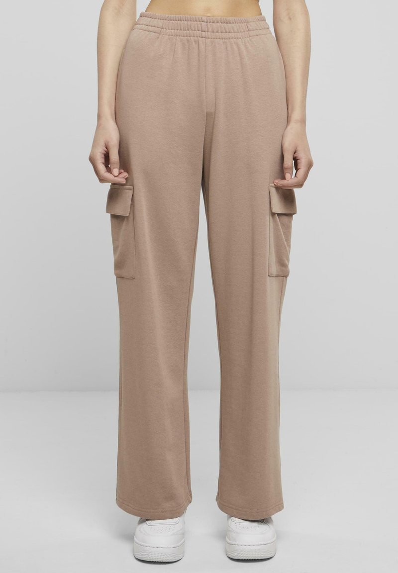 Beige cargobyxor med elastisk midja, vida ben och två sidofickor. Tillverkade av mjukt, töjbart tyg, tillsammans med vita sneakers.