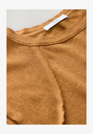 Haut en mélange de coton marron avec une finition texturée, présentant un col rond, des coutures à bords bruts et une coupe décontractée. Étiquette de la marque visible à l'arrière.