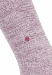 Zbliżenie na jasnofioletową dzianinową skarpetę z małym, okrągłym bordowym logo wyhaftowanym w pobliżu kostki.