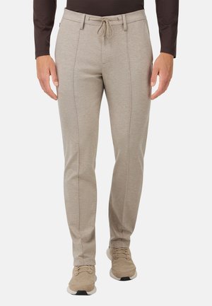Hellgraue Herrenhose mit elastischem Bund und Kordelzug. Verfügt über vertikale Nahtdetails und eine schmal zulaufende Passform. Kombiniert mit beigen Schuhen.