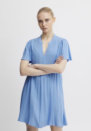 Robe courte bleu clair avec un col rond et de douces manches courtes bouffantes. Le tissu a une apparence texturée et une coupe ample.