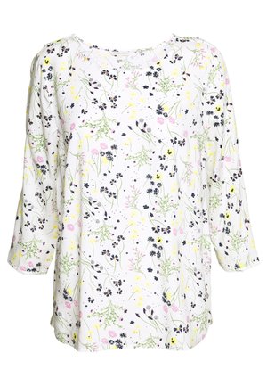 Haut blanc à manches longues avec un col rond, présentant un délicat motif floral en noir, jaune, rose et vert.