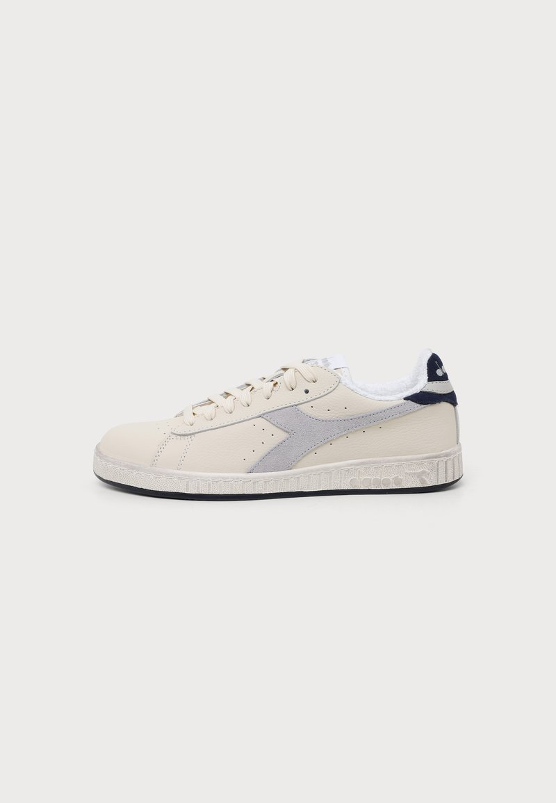 Baskets basses en cuir beige avec détail latéral en suède gris, doublure intérieure blanche et semelle texturée avec fond noir.