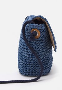 Borsa intrecciata blu con dettaglio in legno rotondo e occhioletto metallico, presenta una fodera morbida e una lunga tracolla intrecciata per il trasporto.