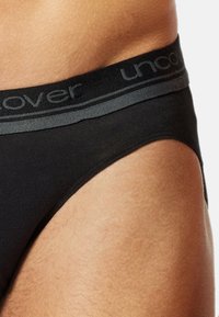 Boxers noirs pour hommes en tissu doux, avec une ceinture élastique grise portant le texte "uncover". Design simple et sans couture avec une coupe ajustée.