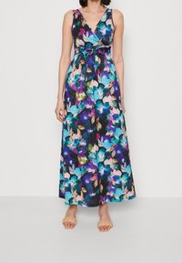 Robe maxi fleurie avec un design croisé et un décolleté en V. Les couleurs incluent le bleu, le violet et le rose sur un fond noir. Comprend une taille à nouer.