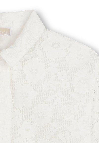 Koronkowa bluzka w kolorze białym, z kwiatowym wzorem, klasycznym kołnierzem, teksturowaną tkaniną i delikatnymi zdobieniami.