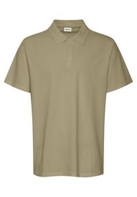 Beige bomullspolo med klassisk krage, korte ermer og rett søm. Har en to-knappers åpning. Ingen mønstre eller aksenter.
