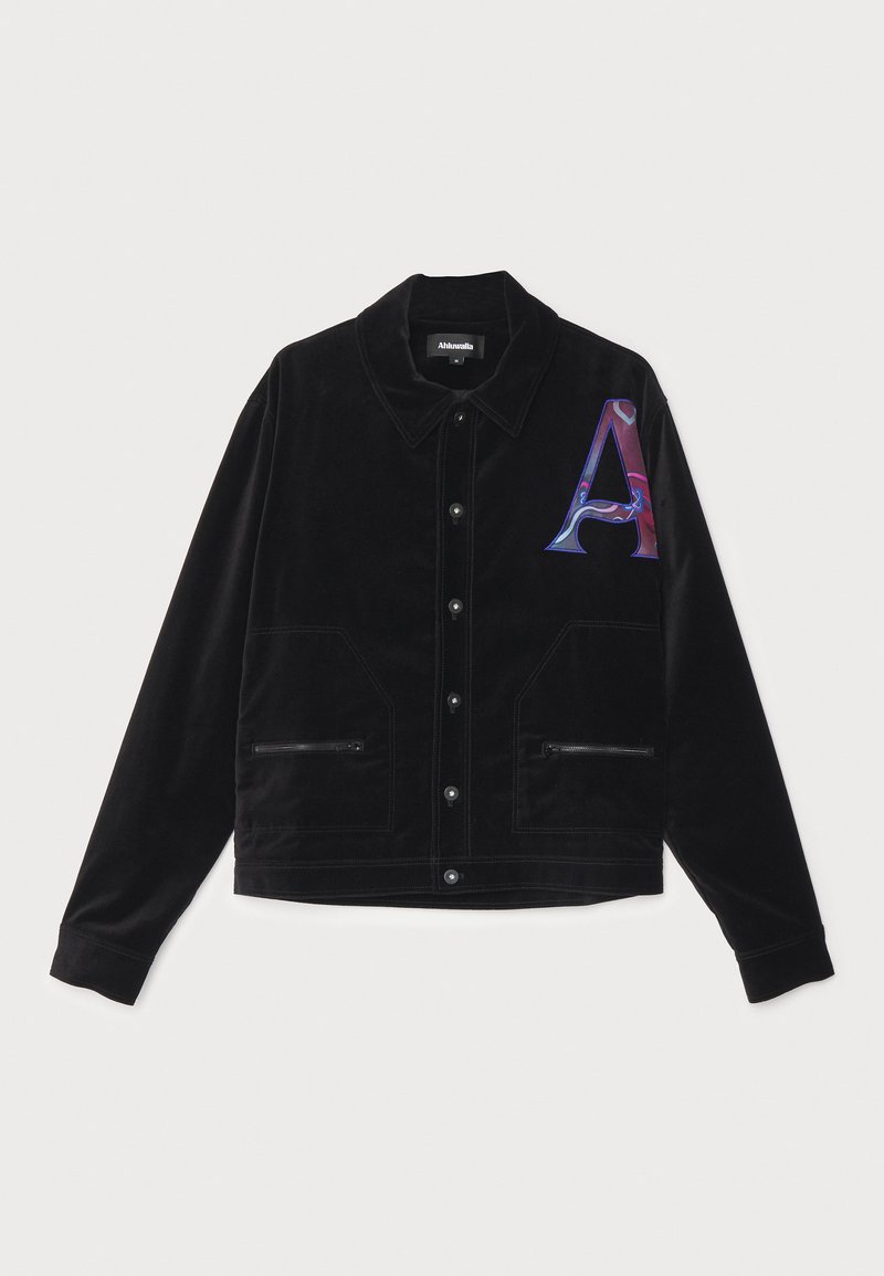 Schwarze Cordjacke mit Knopfverschluss, zwei Reißverschlusstaschen, spitzem Kragen und einem bunten Buchstaben 'A'-Grafik auf dem linken Ärmel.