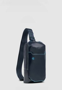 Borsa a tracolla blu navy con superficie liscia, dotata di chiusura con cerniera, tracolla regolabile e dettagli blu a contrasto. Design compatto e funzionale.