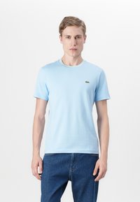 T-shirt à manches courtes bleu clair en coton, avec un col en rib très contrastant et un petit logo brodé sur la poitrine gauche.