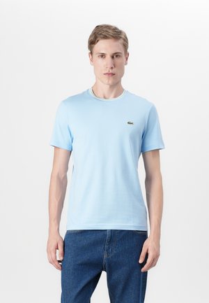 T-shirt azzurro chiaro a maniche corte in cotone, con un col a costine a contrasto e un piccolo logo ricamato sul lato sinistro del petto.