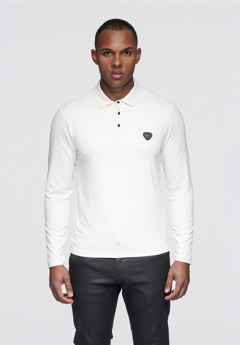 Weißes langärmeliges Polohemd mit klassischem Kragen und drei schwarzen Knöpfen, versehen mit einem schwarzen Logopatch auf der Brust.
