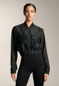 Black, sheer cropped jacket with a stand collar, front zip, and two chest pockets. Features gathered cuffs and a fitted waistband.