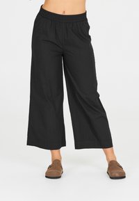 Svarta vida byxor med elastisk midja, tillverkade av lättviktig tyg, med en mjuk textur och ren nederkant.