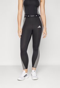 Svart og grå Techfit tights har høy midje, elastisk materiale og en glatt finish med Adidas-logo på hoften.