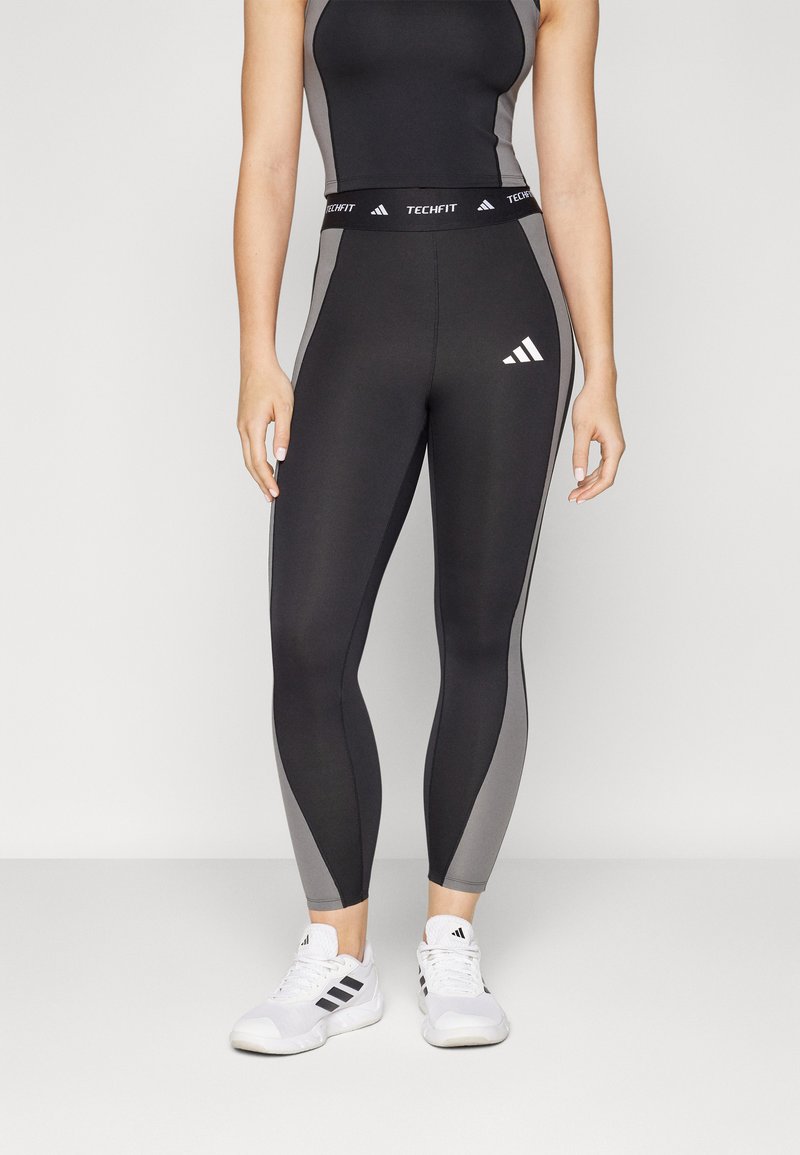 Svart og grå Techfit tights har høy midje, elastisk materiale og en glatt finish med Adidas-logo på hoften.