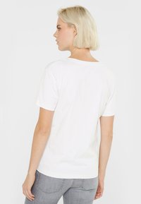 Weißes Baumwoll-T-Shirt mit kurzen Ärmeln und klassischem Rundhalsausschnitt. Glatte Textur, lockere Passform, keine sichtbaren Muster oder Logos.