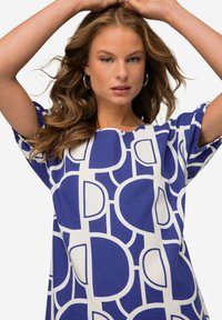 Modrá a bílá šaty se vzorem, které obsahují abstraktní tvary, krátké rukávy, kulatý výstřih a volný střih z lehkého materiálu.