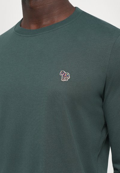 Mørkegrønn langermet skjorte med en liten brodert flerfarget stripete zebra-logo på venstre bryst.