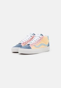 Zapatillas altas que presentan una mezcla de pana azul, rosa y amarilla, cordones blancos y una suela de goma blanca con un detalle de logo en forma de ola.