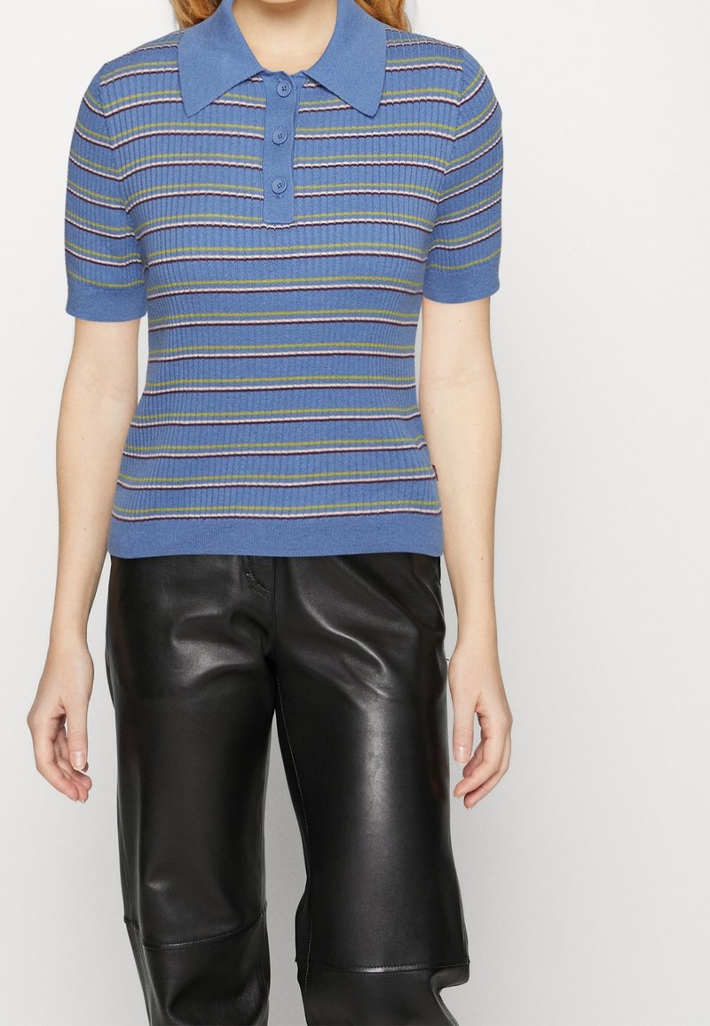 Blå polo-tröja med korta ärmar, ribbad textur och horisontella ränder i lila, grön och vit. Har en krage och en tre-knapps placket.