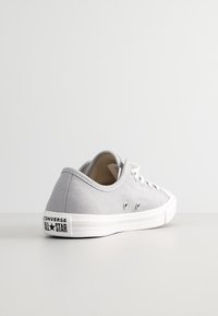 Szare płócienne trampki typu low-top z białą gumową podeszwą i oczkami. Zawierają logo Converse All Star na pięcie. Prosty i funkcjonalny design.