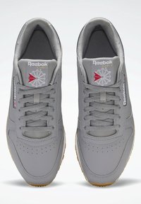Harmaat Reebok-tennarit, joissa on sileä nahkapäällinen, verkkokieli, kumipohja ja koristeelliset yksityiskohdat, kuten logo ja tähtikuvio.