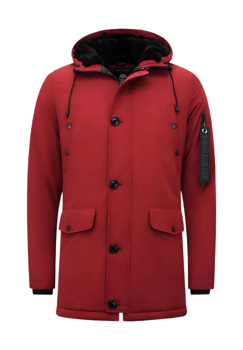 Rode geïsoleerde parka met een met bont gevoerde capuchon, zwarte knopen en twee zijzakken. Heeft een label op de mouw en elastische manchetten.