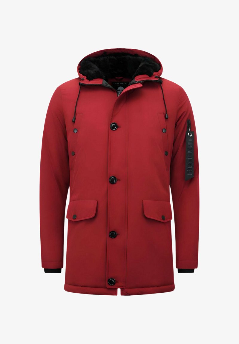 Rode geïsoleerde parka met een met bont gevoerde capuchon, zwarte knopen en twee zijzakken. Heeft een label op de mouw en elastische manchetten.