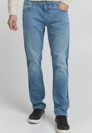 Lyseblå denimjeans med slim fit, med subtil fading, fem lommer og en klassisk knapp- og glidelås-lukking, kombinert med svarte sneakers.
