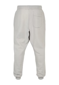 Light gray sweatpants with a tapered fit, elastic waistband, ribbed cuffs, and a single back pocket. Fabric has a smooth texture.