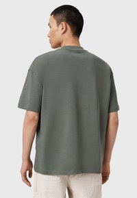 Olivengrøn kortærmet t-shirt med afslappet pasform, rund halsudskæring og blød tekstur. Enkelt design uden synlige mønstre eller accenter.