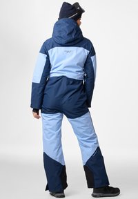 Marineblauer und hellblauer Skianzug mit Kapuze, kontrastierenden Einsätzen und Logo auf dem Rücken. Besteht aus wasserabweisendem Material und hat verstellbare Bündchen.