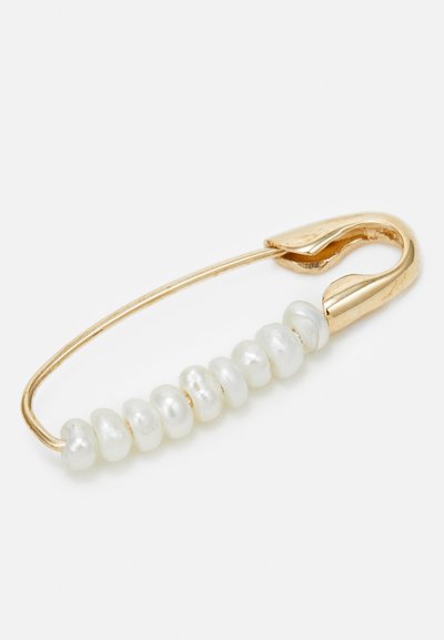 Alfinete de segurança dourado com uma fileira de pérolas brancas presas. As pérolas variam em forma e tamanho, criando um detalhe texturizado e elegante.