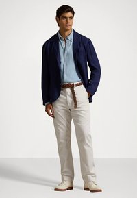 Tamsiai mėlynas lininis švarkas, šviesiai mėlyni marškiniai su sagutėmis, balti kelnės ir rudas pintas diržas. Rudi bateliai su raišteliais užbaigia aprangą.