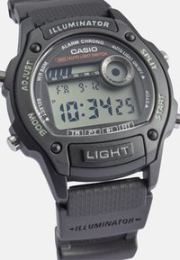 Orologio digitale da polso con cinturino in gomma nera, cassa rotonda, grande display LCD e pulsanti etichettati "LUCE", "DIVIDI" e "REGOLA". Impermeabile.