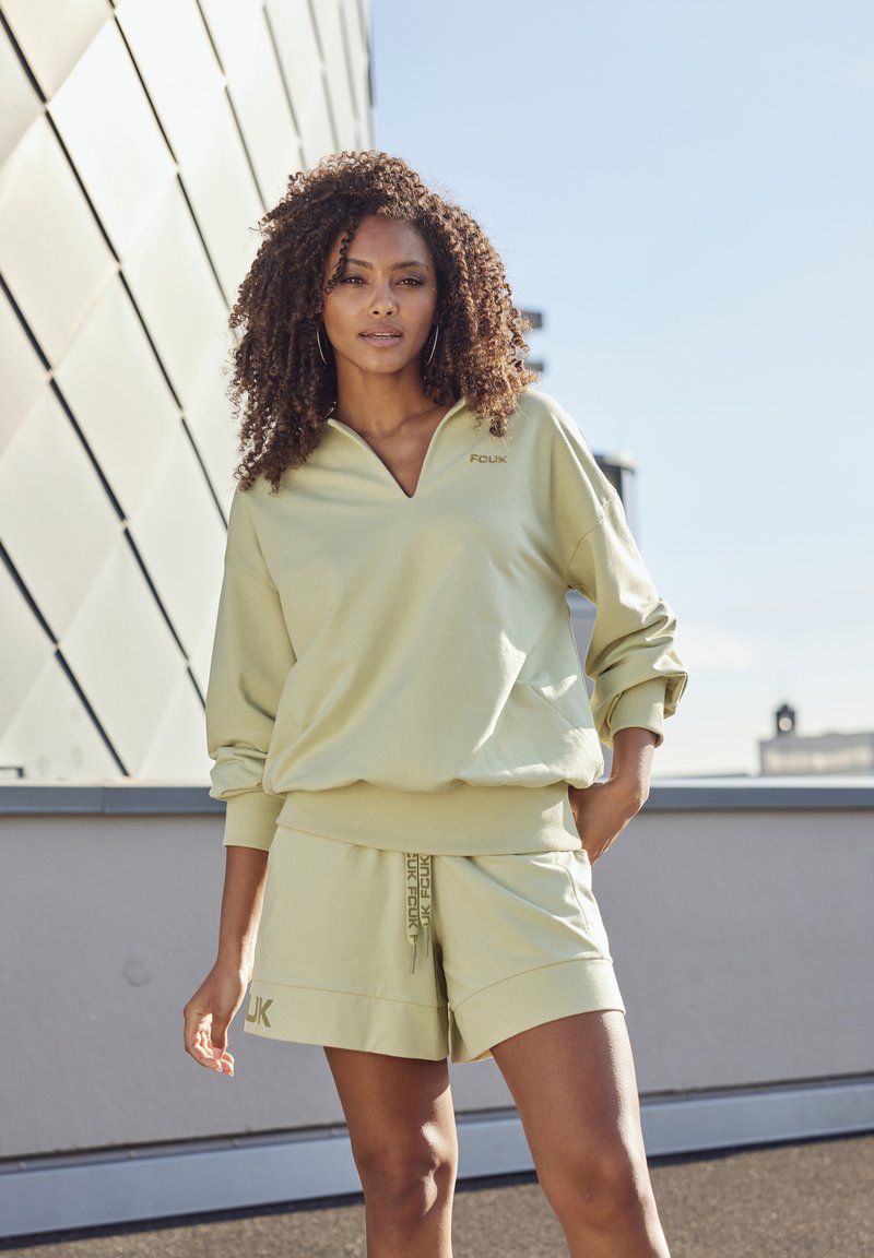 Light green sweatshirt with a v-neck and branded "FCUK" design, paired with matching shorts featuring side lettering and drawstring.