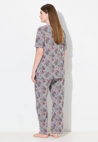 Gemustertes Schlafanzug-Set mit kurzen Ärmeln und langen Hosen. Das Material ist leicht, mit einem weißen Grund und buntem abstraktem Druck.