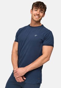 Granatowy t-shirt z krótkim rękawem, wykonany z miękkiej bawełny, z małym białym logo na piersi i okrągłym dekoltem.