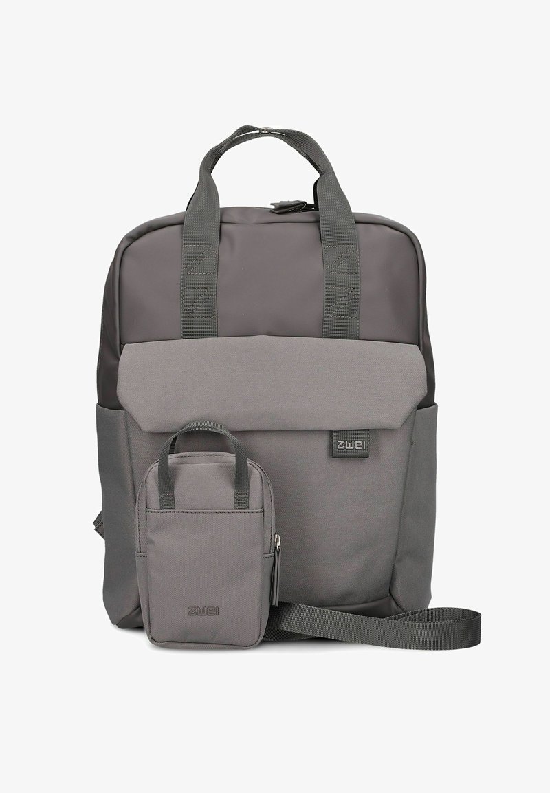 Mochila de tela gris con un bolsillo frontal, dos asas en la parte superior y correa de hombro ajustable. Presenta un diseño simple y un tamaño moderado.