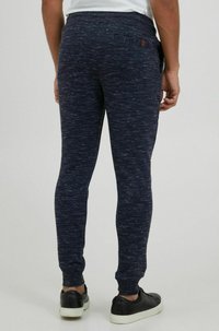 Navy jogger pants made of textured fabric, featuring a slim fit, elastic waistband, side pockets, and a small back pocket with a button.