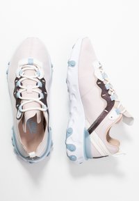 Ljust rosa träningsskor med ett texturerat mönster, med blå accenter, vita snören och en unik sula med cirkulära grepp.