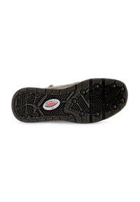Semelle de chaussure en caoutchouc noir avec un motif de crampons texturé, arborant un logo de marque rouge et blanc au centre. Les formes incluent des cercles et des zigzags.