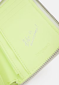 Limoengroene kaarthouder met rits, voorzien van Kaartsleuven, metallic stiksels en een geperst bericht met de tekst "Het leven is geweldig!" aan de binnenkant.