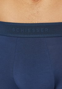 Marinblå boxershorts med en texturerad, elastisk midjeband med präglat varumärke "SCHIESSER." Slät tyg med en figurnära design.