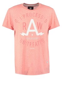 Jasnoróżowa koszulka bawełniana z krótkimi rękawami, z dużym białym napisem graficznym "RAW" oraz towarzyszącymi frazami nadrukowanymi z przodu.
