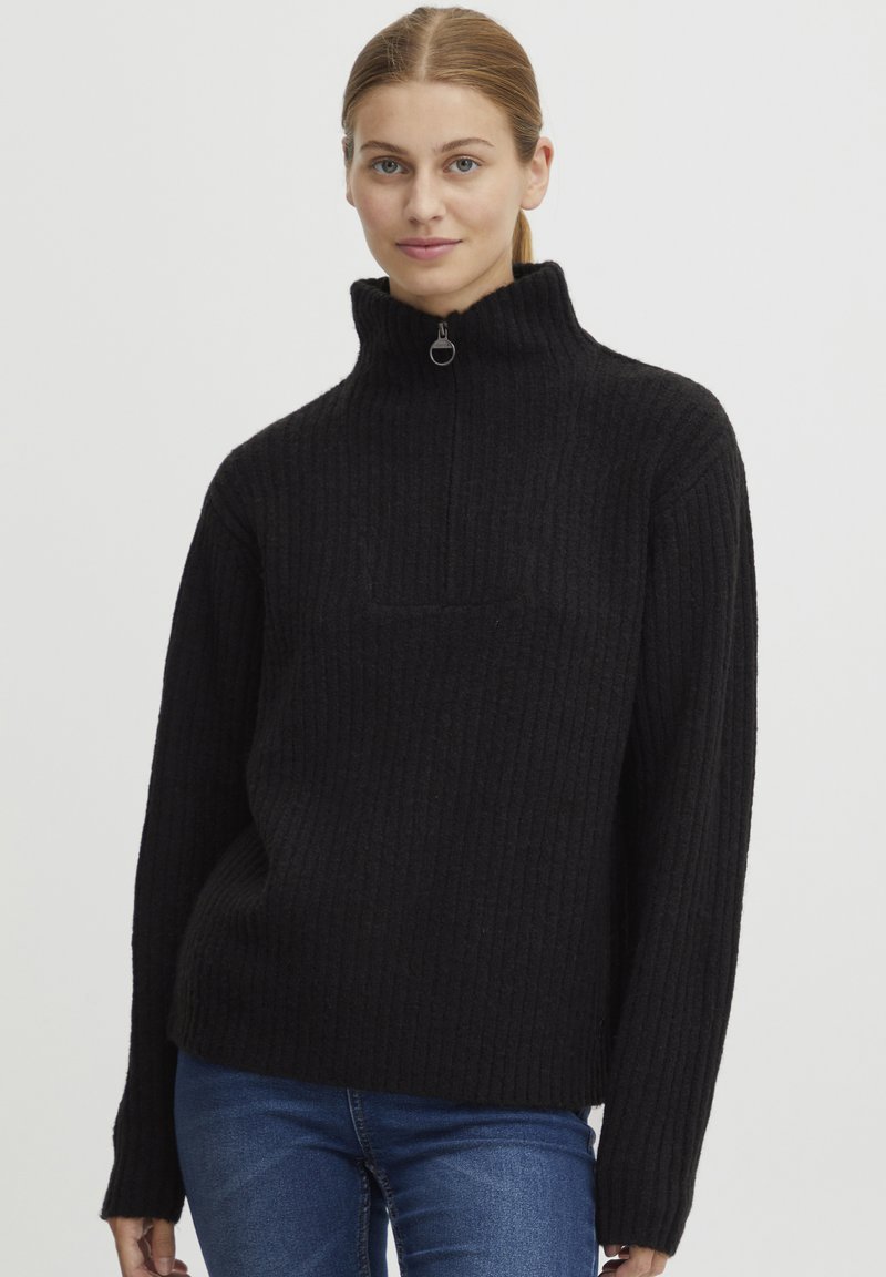 Maglione nero a costine con colletto alto e mezza zip. Presenta maniche lunghe e una vestibilità rilassata. Texture liscia.