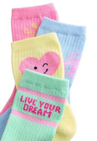 Barvne bombažne nogavice: roza s srcem, svetlo modre s vzorcem, rumene s srcem in zelene z napisom »ŽIVI SVOJ SANJE«.